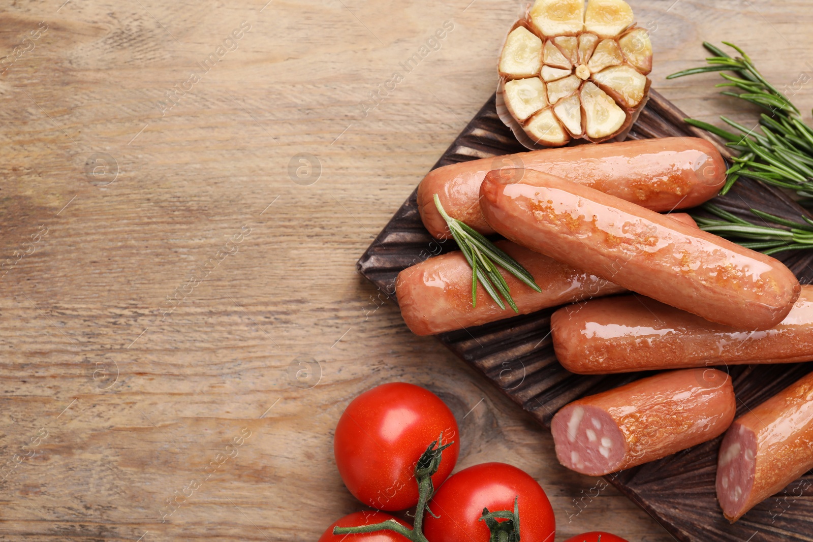 Photo of Delicious vegan sausages, garlic and tomatoes on wooden table, flat lay. Space for text