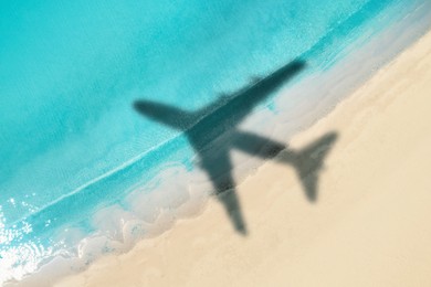 Image of Shadow of airplane above beautiful sandy beach and sea, aerial view. Summer vacation