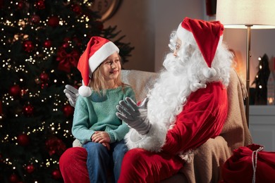 Merry Christmas. Little girl sitting on Santa's knee at home