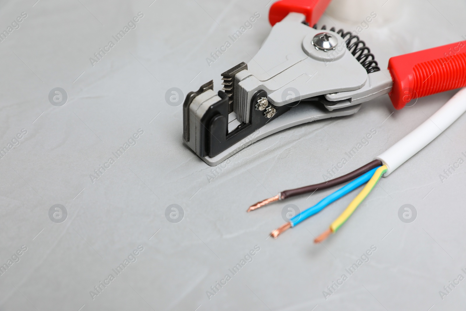 Photo of Cutters and stripped wire on light gray table, closeup. Space for text