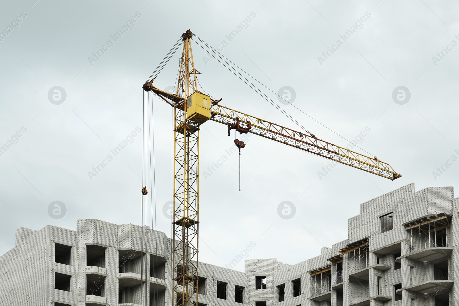 Photo of Construction site with tower crane near unfinished building, low angle view