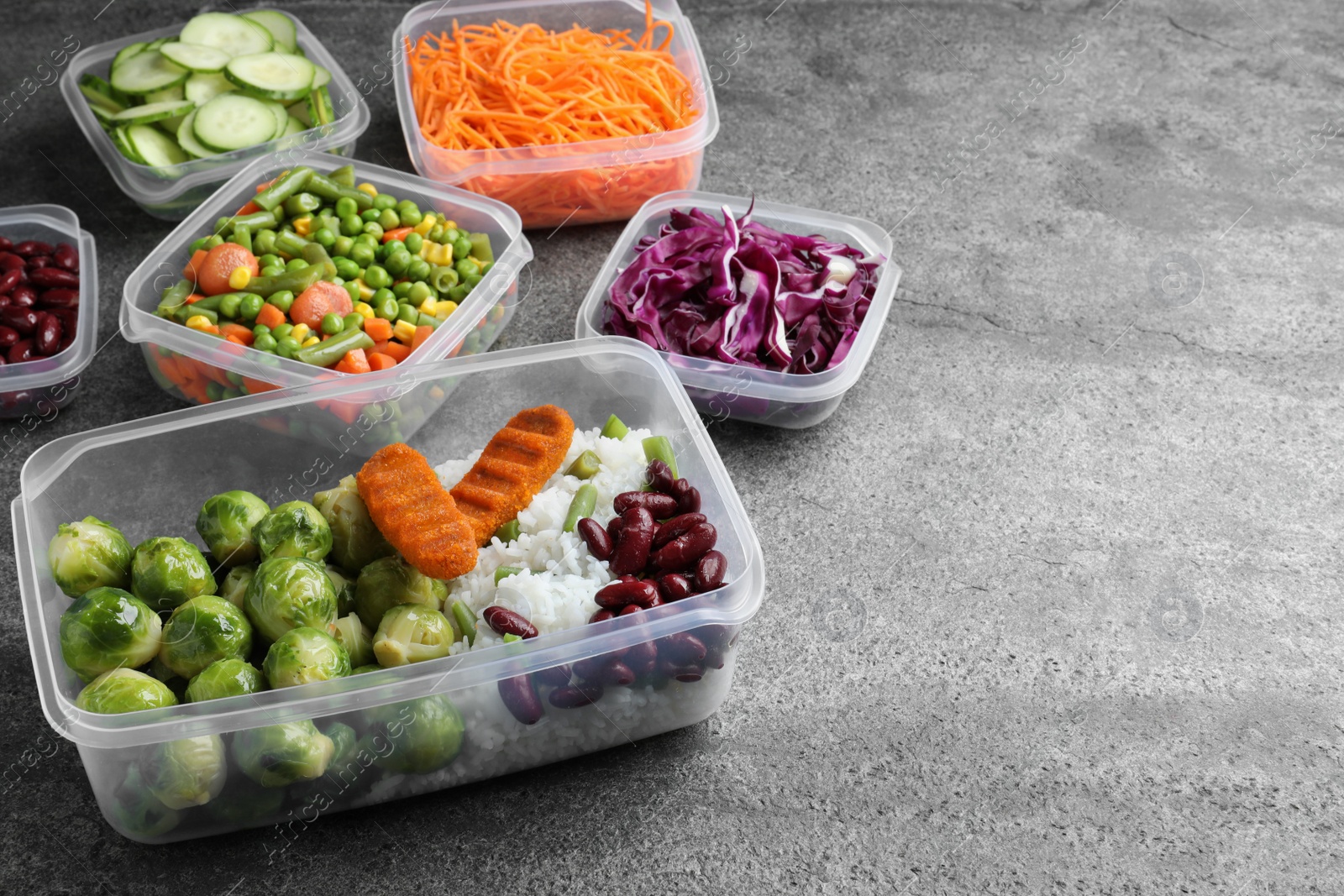 Photo of Set of plastic containers with fresh food on grey   table, space for text