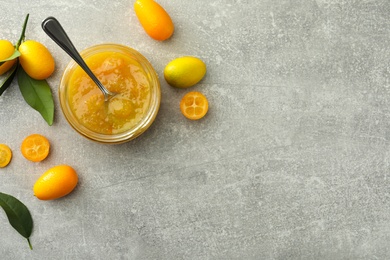 Delicious kumquat jam and fresh fruits on light grey table, flat lay. Space for text