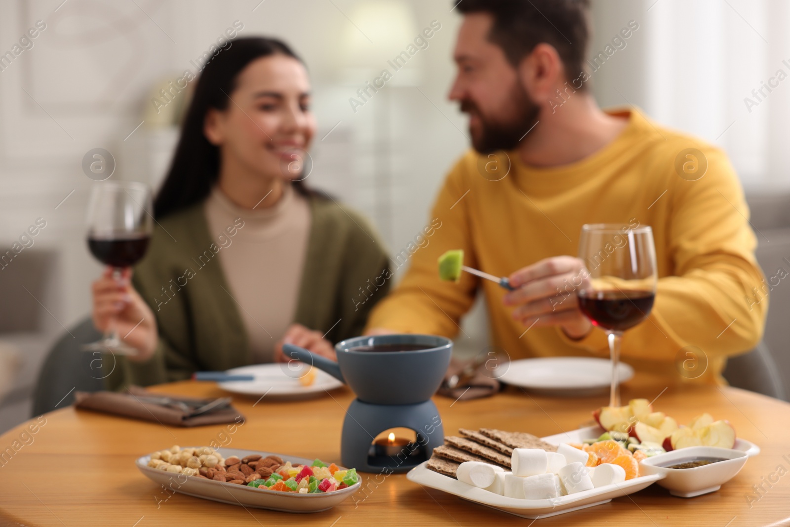 Photo of Affectionate couple enjoying chocolate fondue during romantic date indoors, selective focus