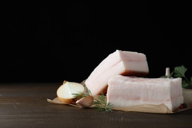 Photo of Tasty salt pork with herbs, onion and garlic on wooden table, space for text