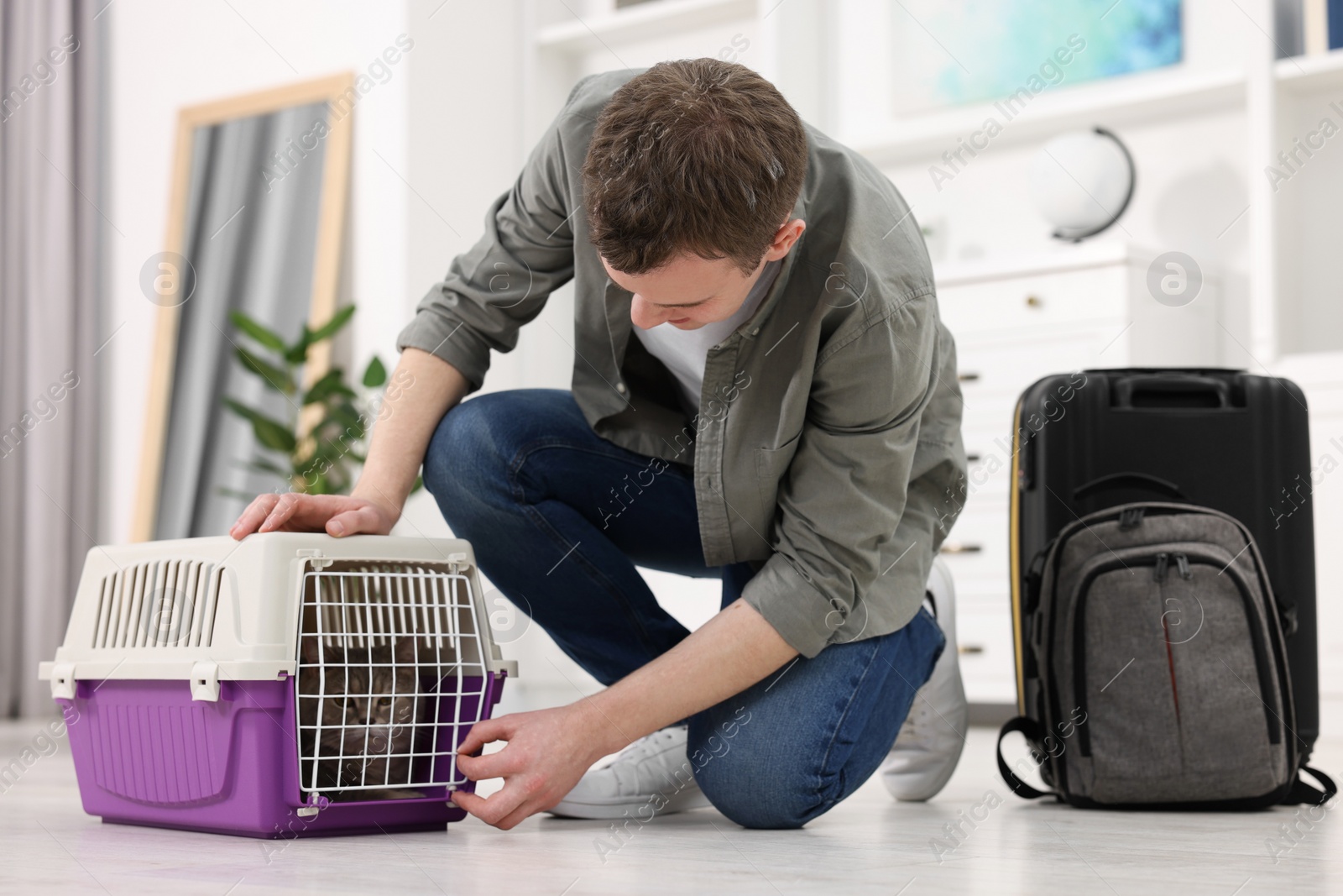 Photo of Travel with pet. Man closing carrier with cat at home