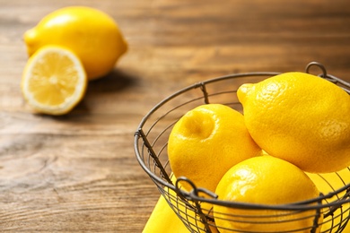 Basket with ripe lemons on wooden background, closeup