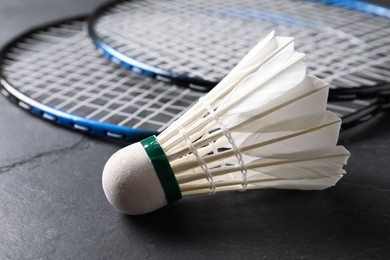 Feather badminton shuttlecock and rackets on grey textured table, closeup