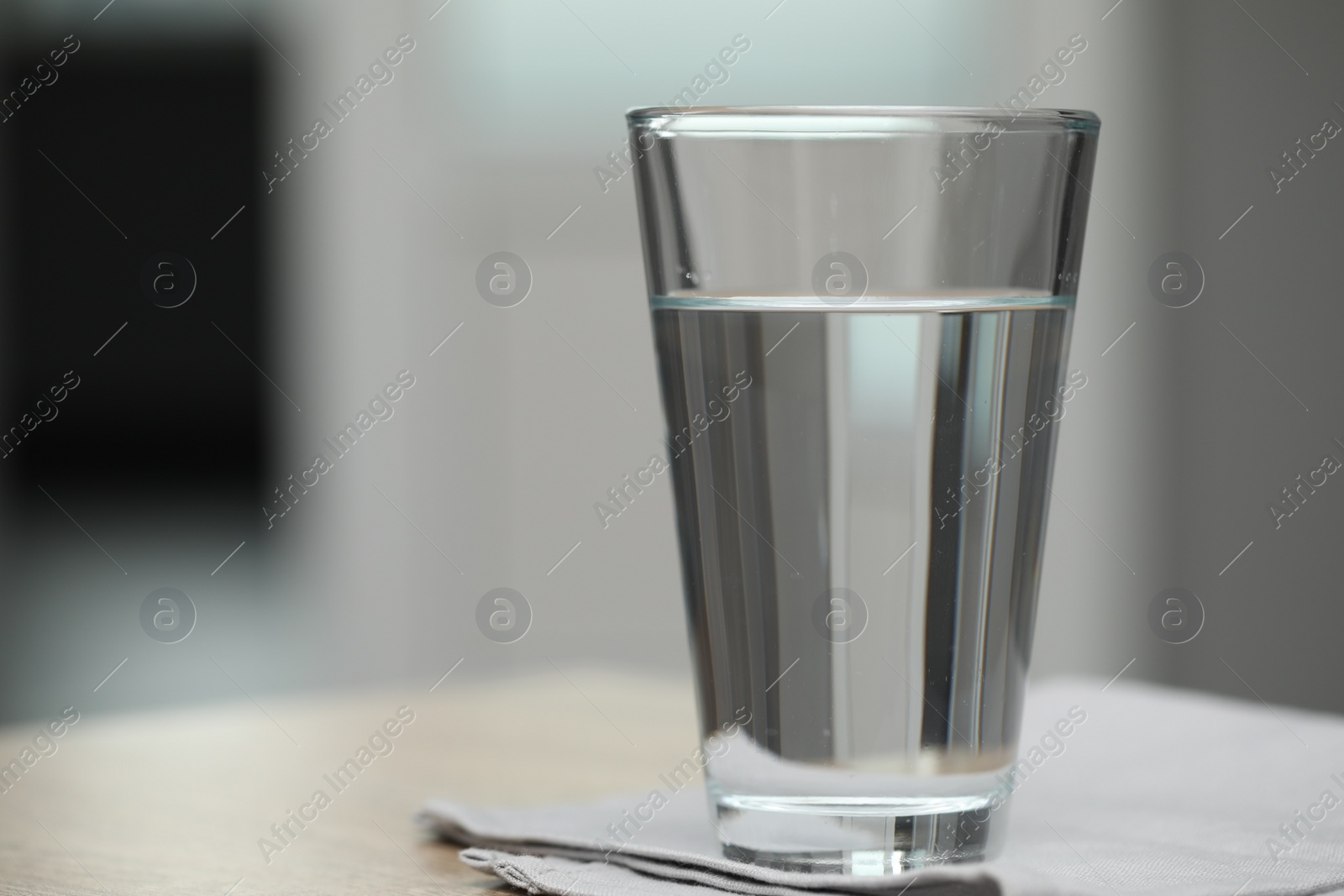 Photo of Glass of pure water on table against blurred background, space for text