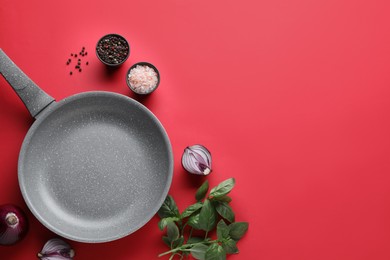 Flat lay composition with frying pan and fresh products on red background, space for text