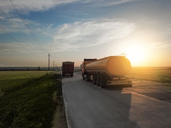 Photo of Modern trucks parked on country road at sunset