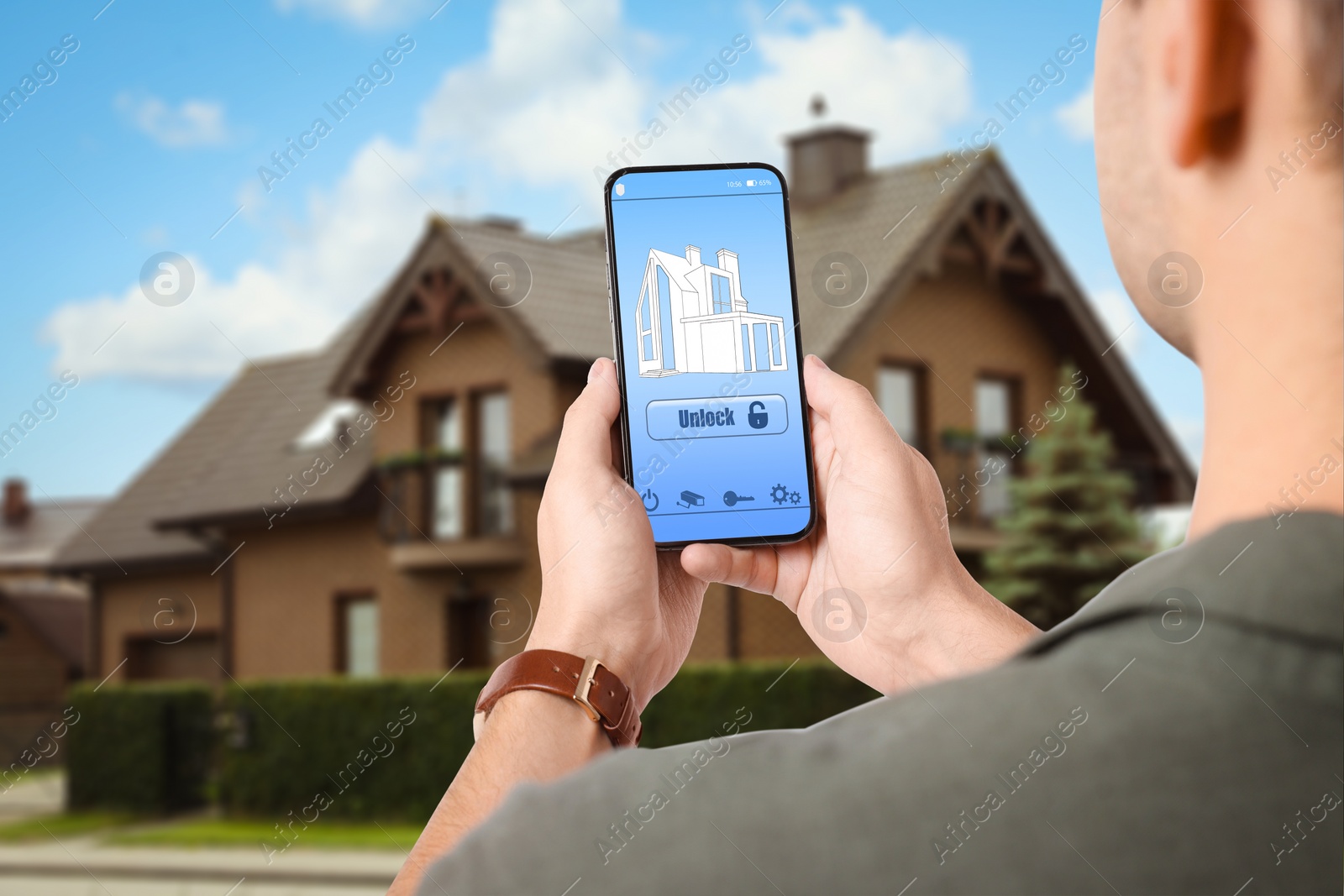 Image of Man using home security system application on smartphone outdoors, closeup