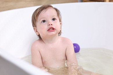 Photo of Cute little child bathing in tub at home