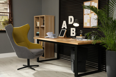 Photo of Comfortable workplace with wooden table and armchair