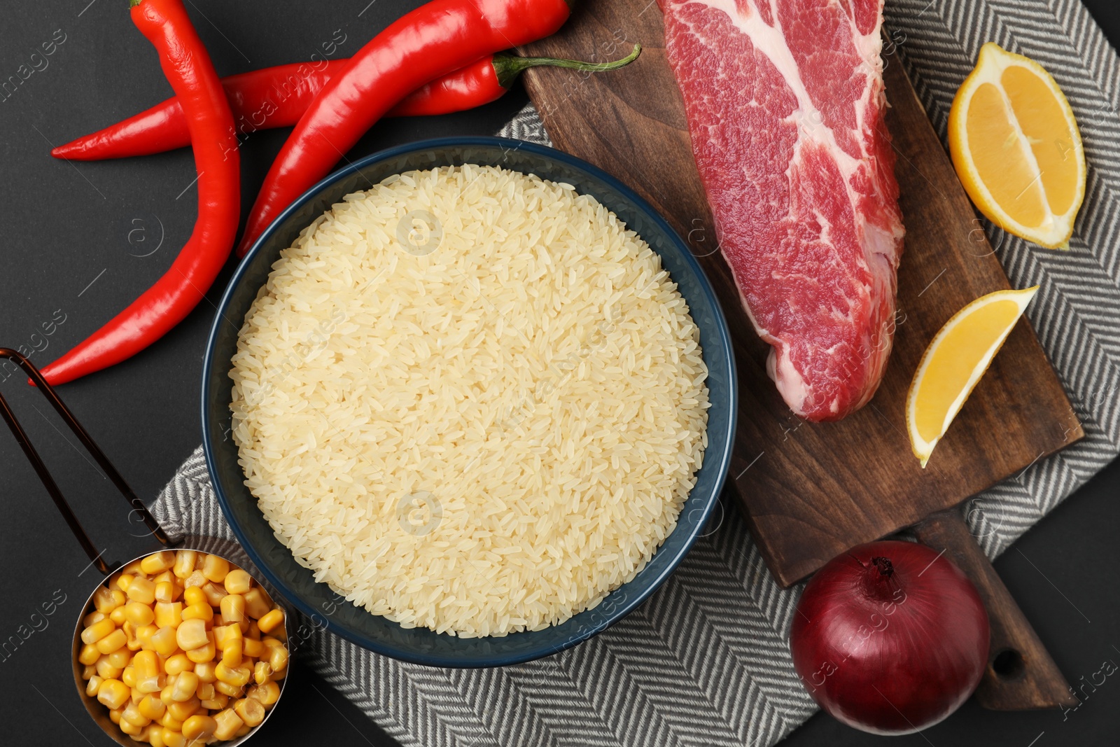 Photo of Flat lay composition with different ingredients on black background. Risotto recipe