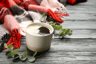 Composition with hot drink and warm plaid on black wooden table