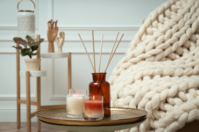 Photo of Air reed freshener and burning candles on table indoors. Interior elements