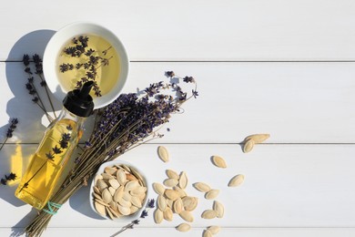 Photo of Healthy cooking oil, lavender flowers and pumpkin seeds on white wooden table, flat lay. Space for text