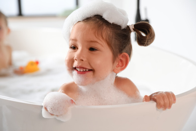 Photo of Cute little girl taking bubble bath at home