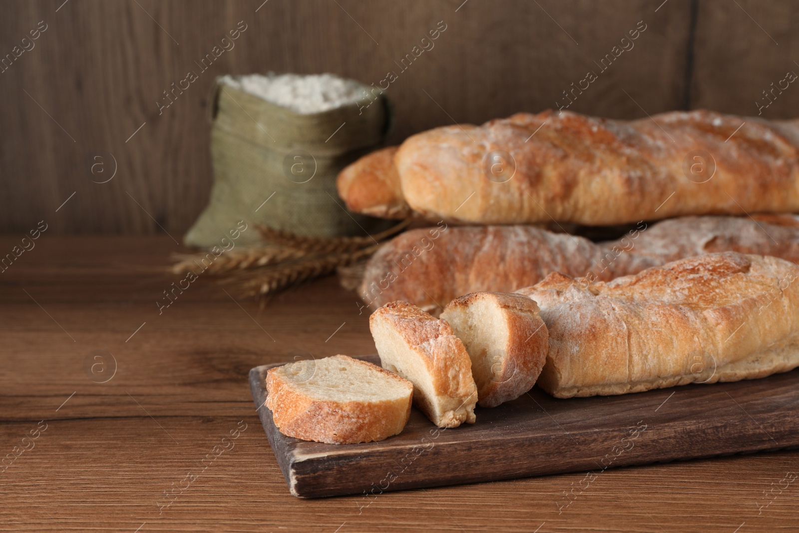Photo of Fresh crispy baguettes on wooden table. Space for text