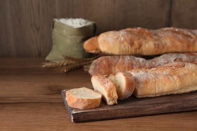 Fresh crispy baguettes on wooden table. Space for text