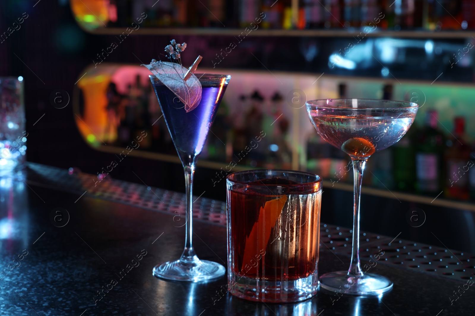 Photo of Different fresh alcoholic cocktails on counter in bar