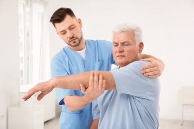 Young physiotherapist working with senior patient in clinic