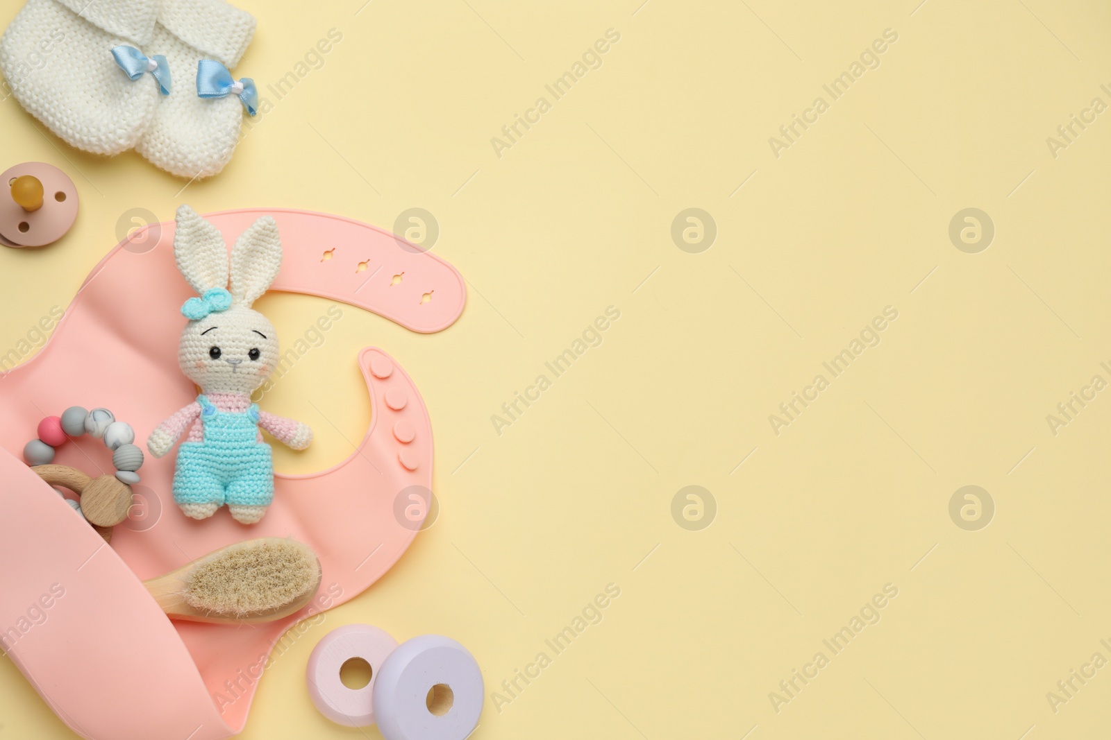 Photo of Flat lay composition with baby accessories and bib on yellow background, space for text