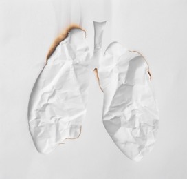 Photo of Smoked cutout in shape of human lungs on crumpled paper, top view. No smoking concept