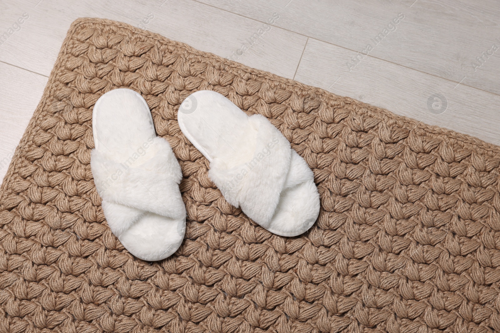 Photo of Soft white slippers on carpet in room. Space for text