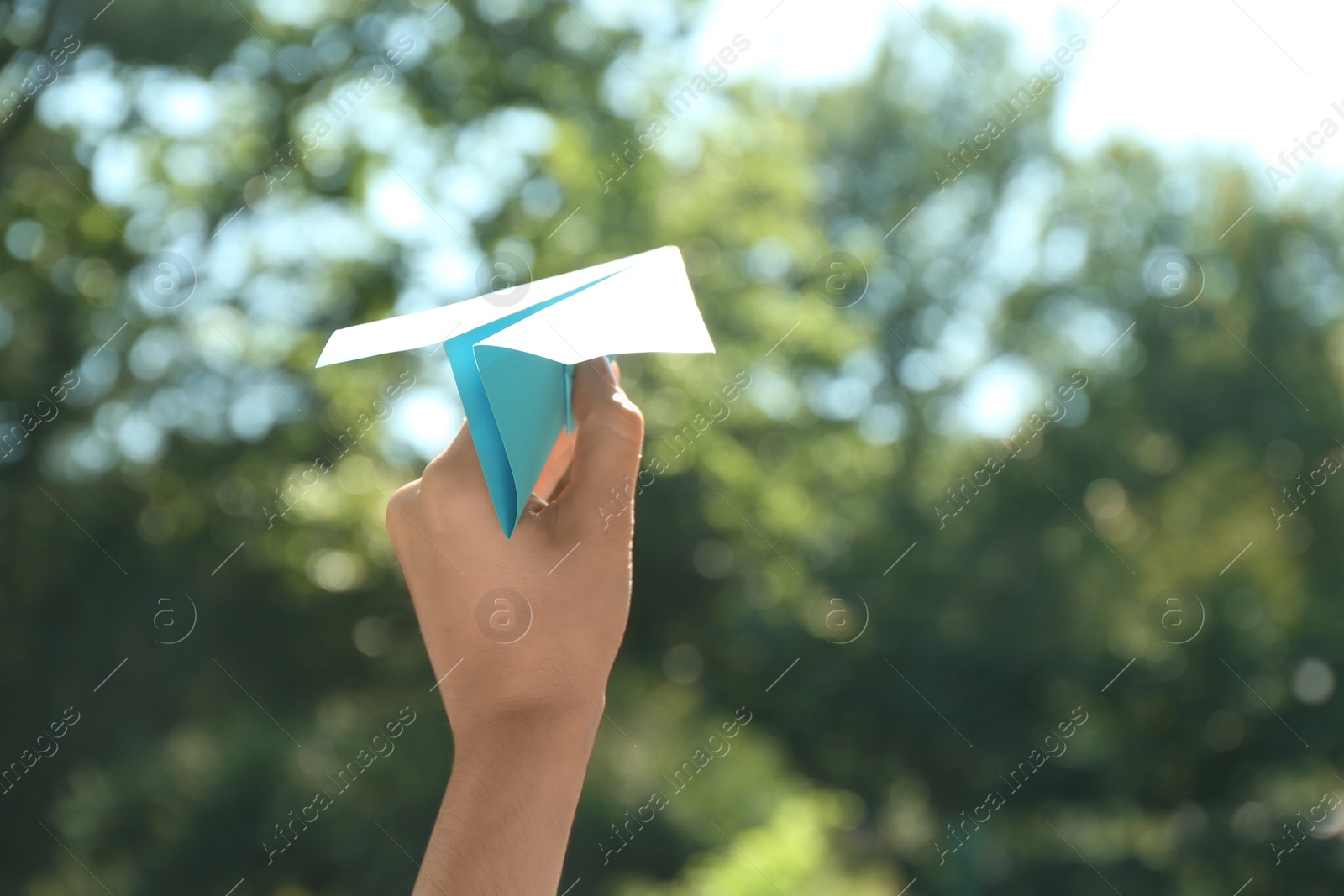 Photo of Woman holding paper plane outdoors, closeup. Space for text