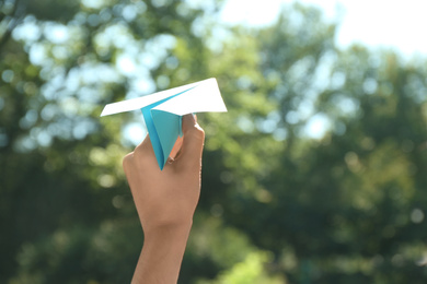 Photo of Woman holding paper plane outdoors, closeup. Space for text