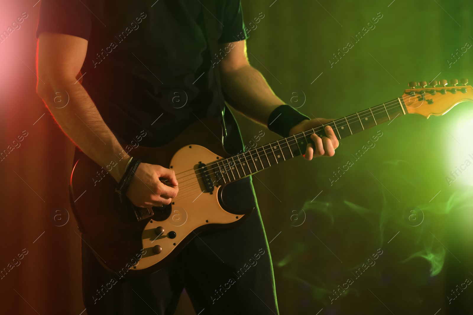 Photo of Man playing electric guitar on stage, closeup. Rock music