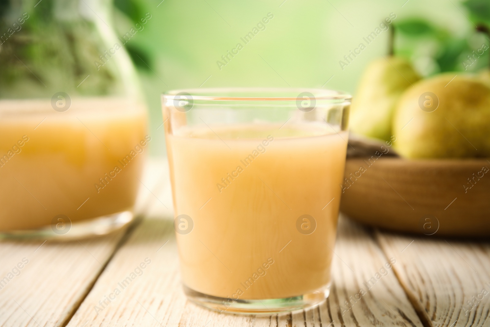 Photo of Fresh pear juice in glass on white wooden table, closeup