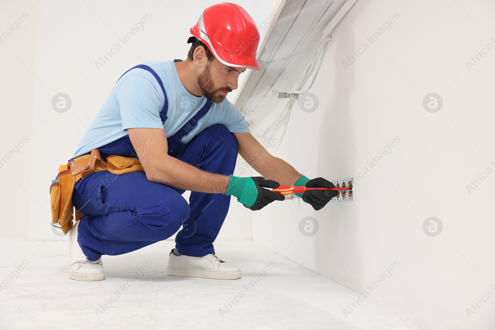 Photo of Electrician with screwdriver repairing power sockets indoors