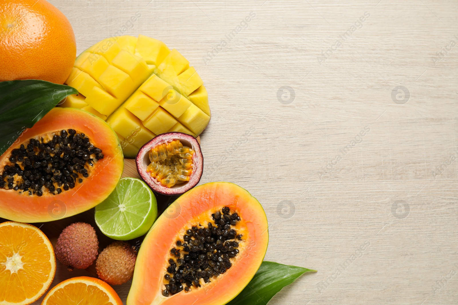 Photo of Fresh ripe papaya and other fruits on white wooden table, flat lay. Space for text