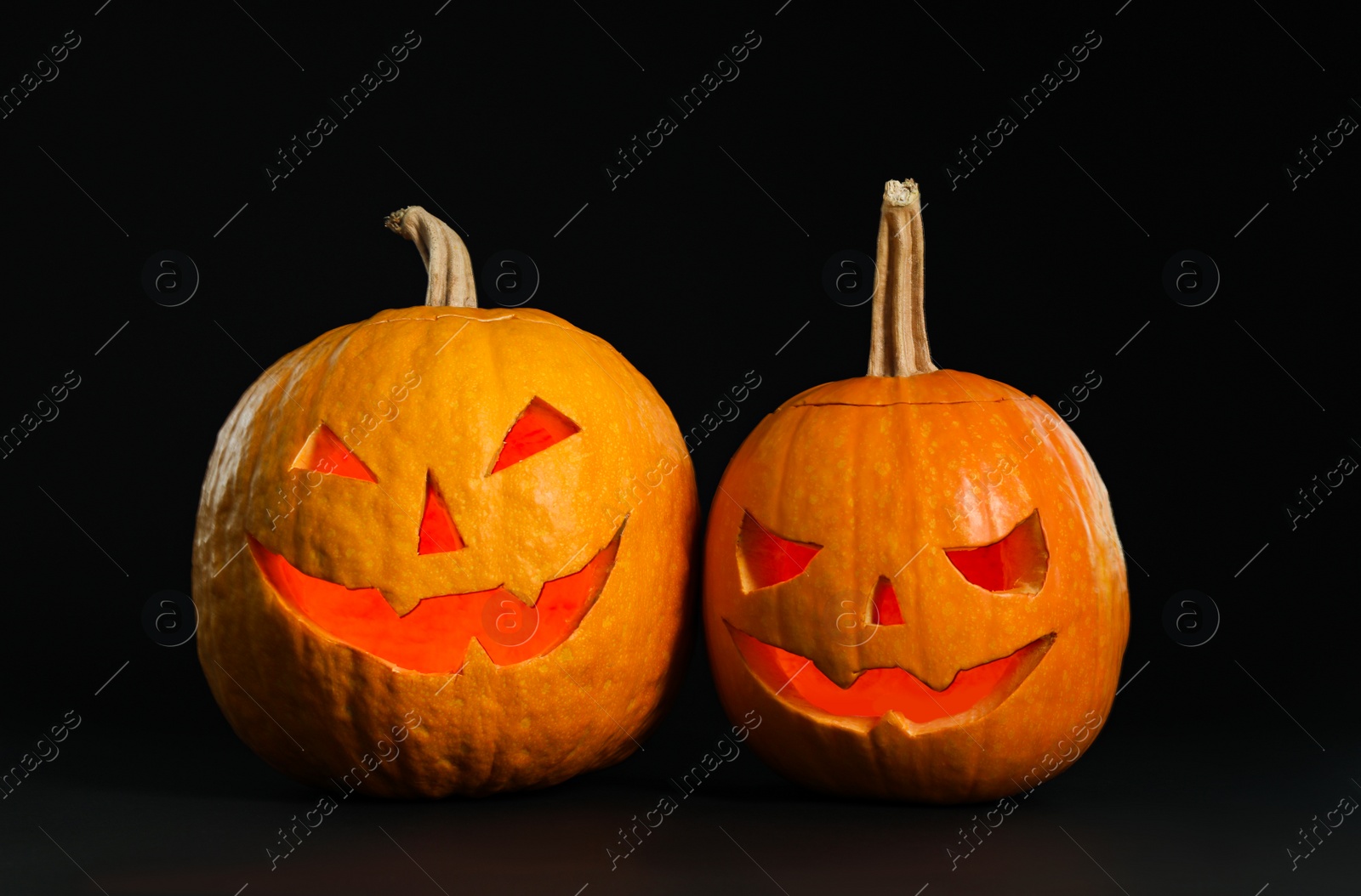 Photo of Pumpkin heads on black background. Jack lantern - traditional Halloween decor
