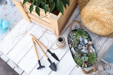 Composition with gardening tools and plants on white wooden table, above view