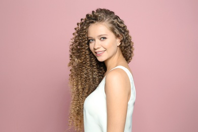 Portrait of beautiful young woman with shiny wavy hair on color background