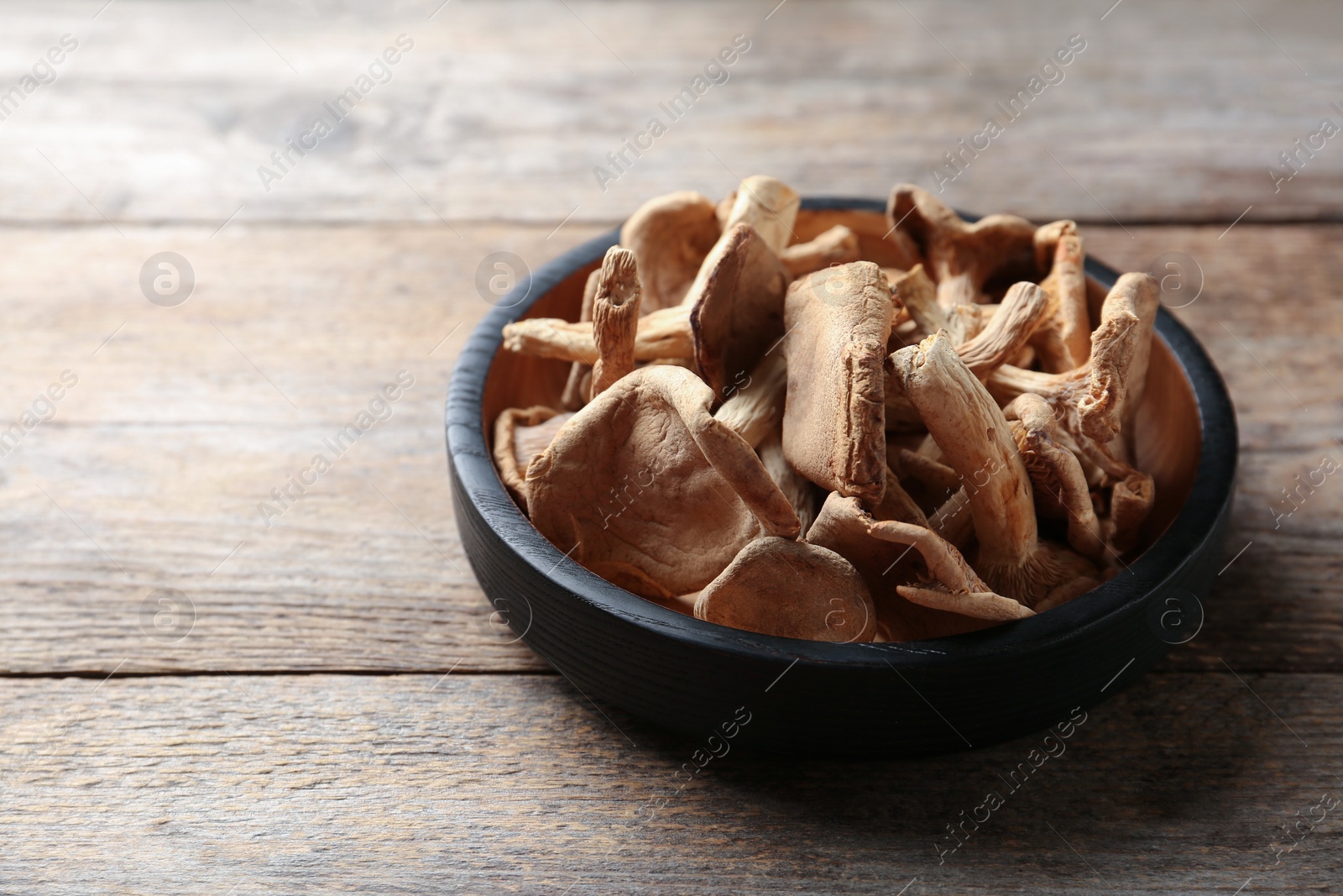 Photo of Plate of dried mushrooms on wooden background. Space for text