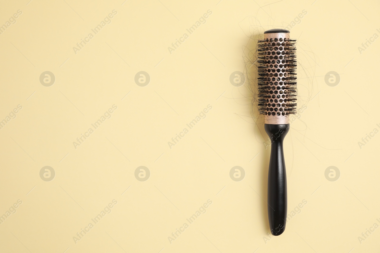 Photo of Professional brush with lost hair on beige background, top view. Space for text