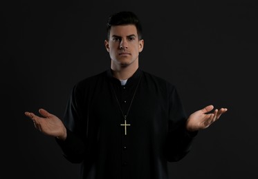 Photo of Priest wearing cassock with clerical collar on black background