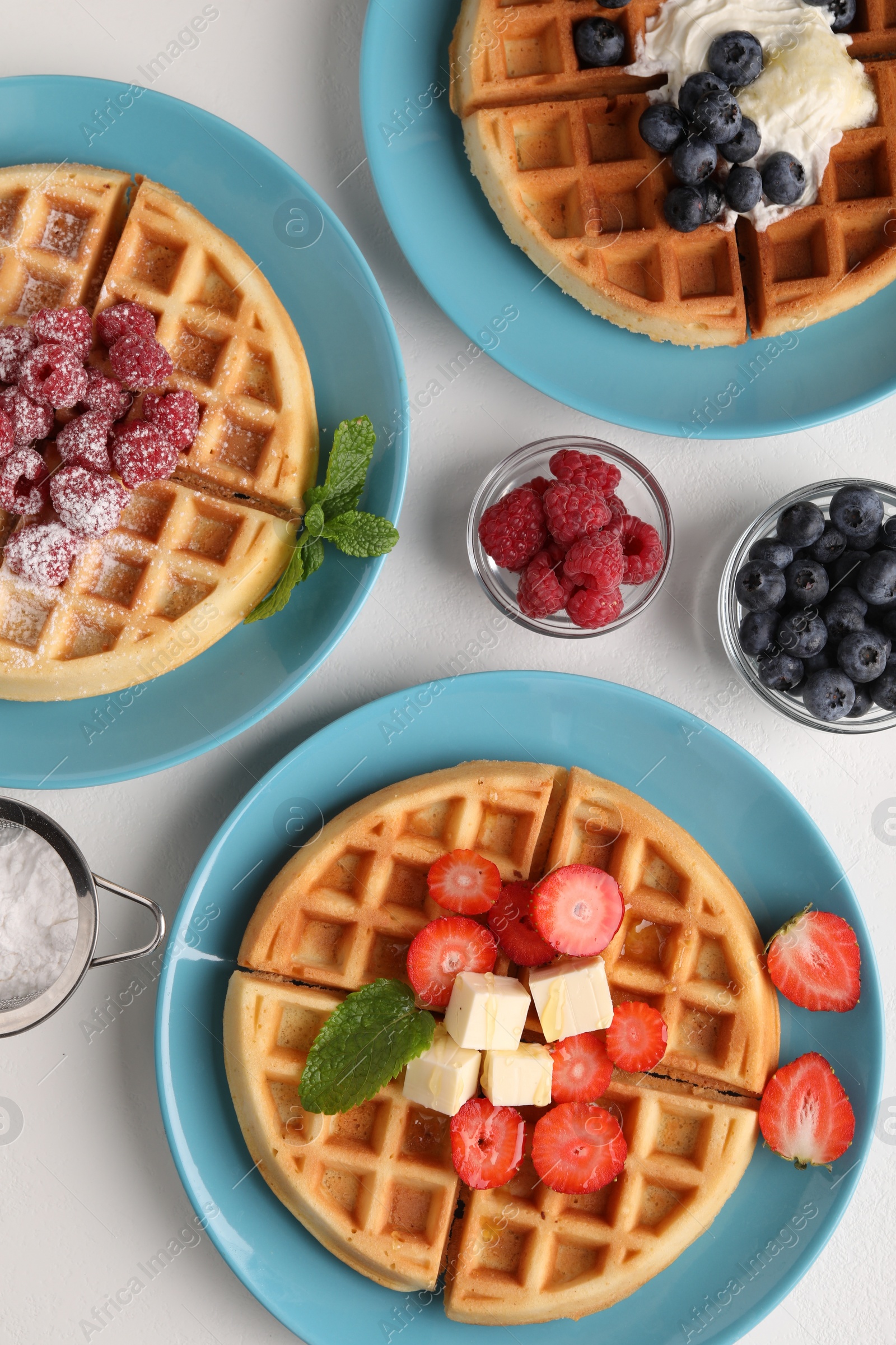 Photo of Tasty Belgian waffles with fresh berries served on white table, flat lay