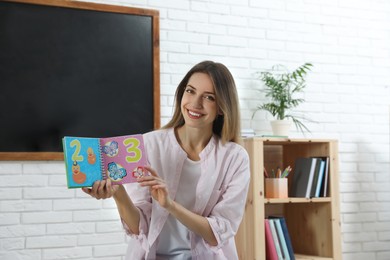 Happy female English teacher giving lesson in elementary school