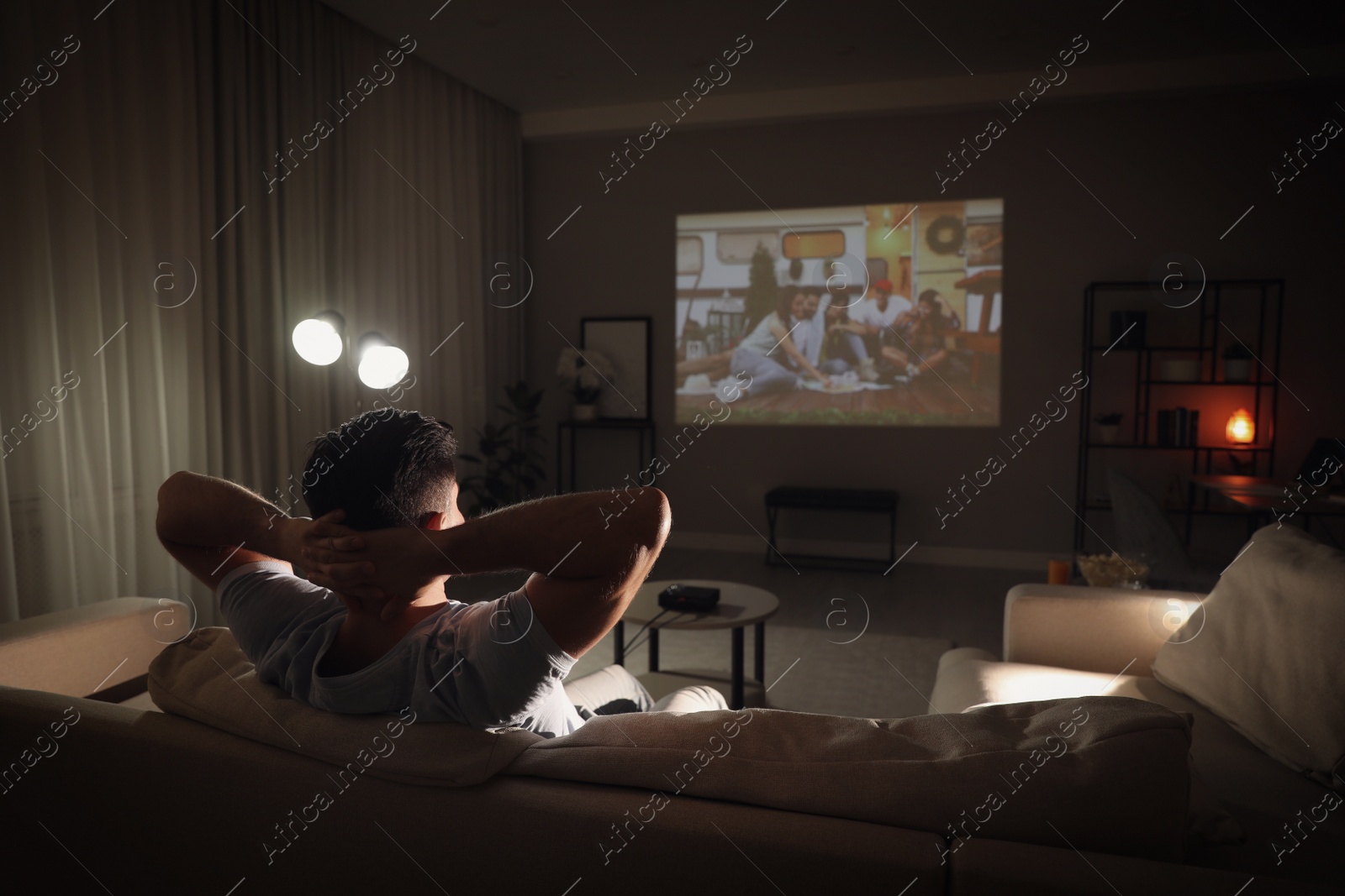 Photo of Man watching movie on sofa at night, back view. Space for text