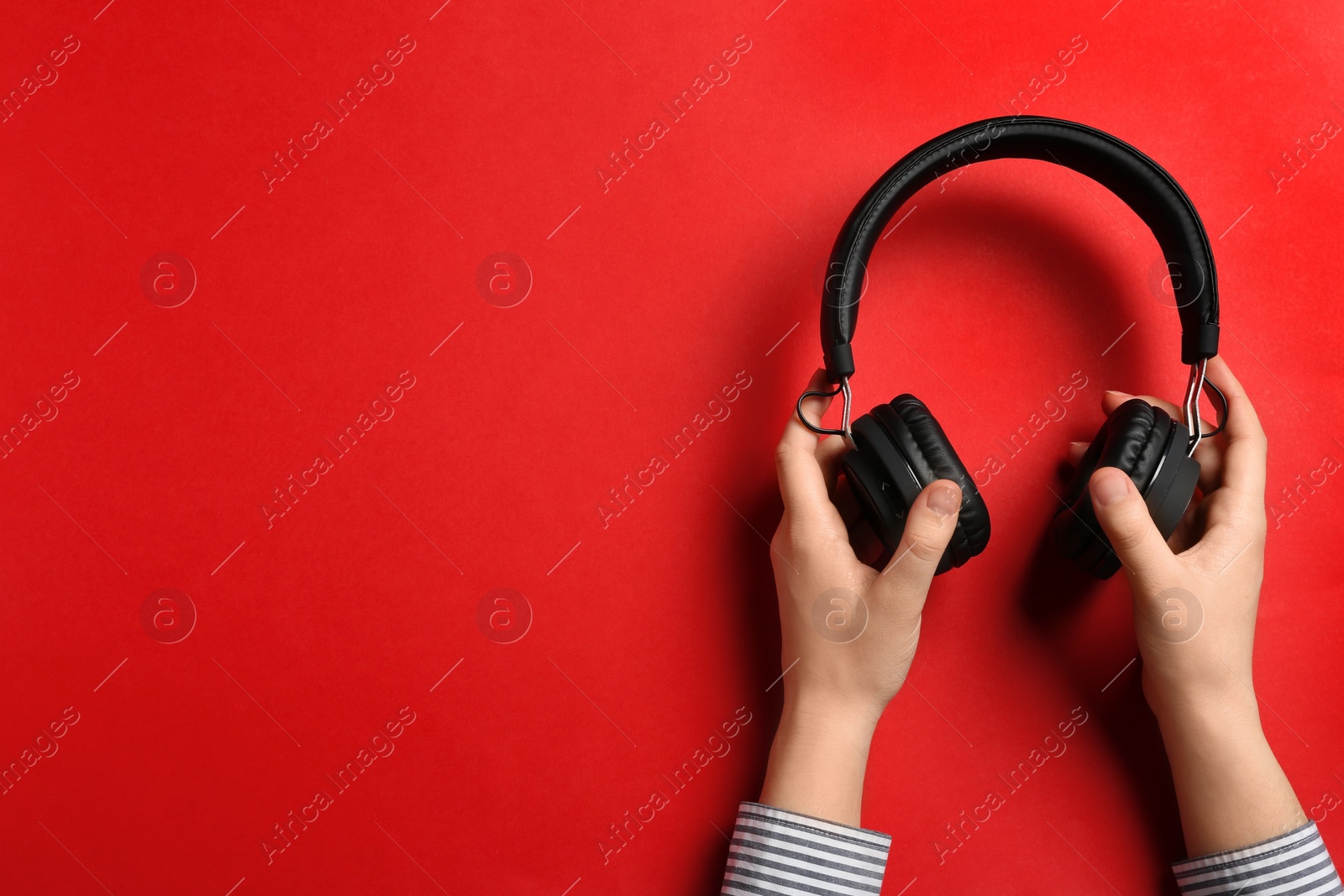 Photo of Woman holding stylish headphones on color background, closeup. Space for text