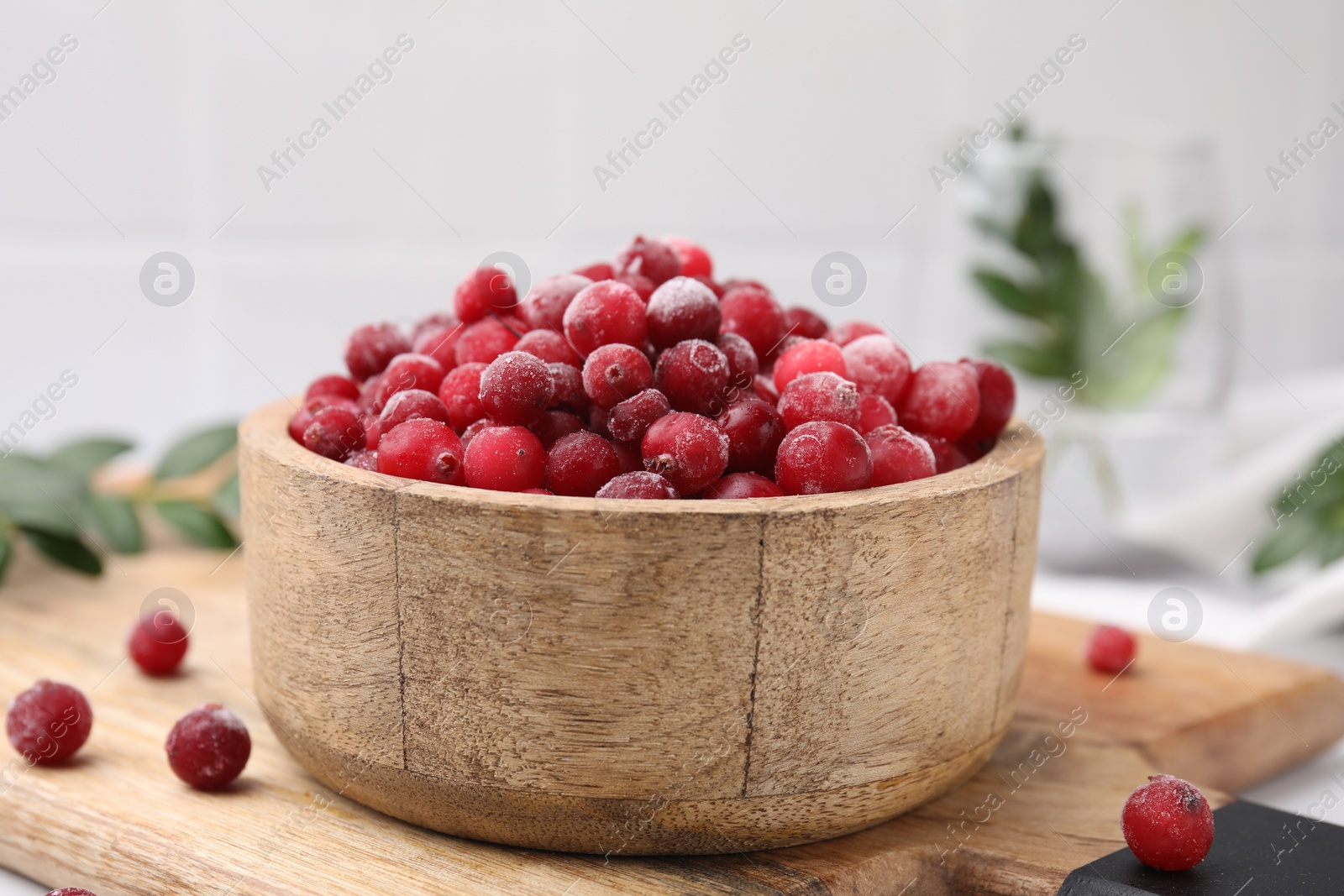 Photo of Frozen red cranberries in bowl on table, closeup