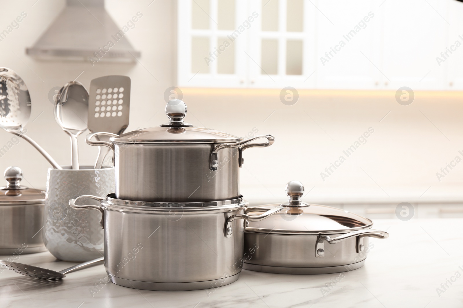 Photo of Set of stainless steel cookware and kitchen utensils on white table indoors, space for text