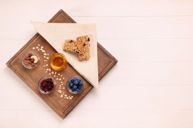 Photo of Tasty granola bars served on white wooden table, top view. Space for text