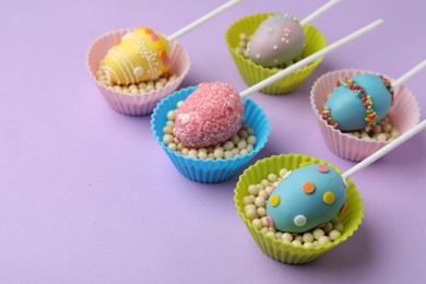 Photo of Egg shaped cake pops for Easter celebration on violet background